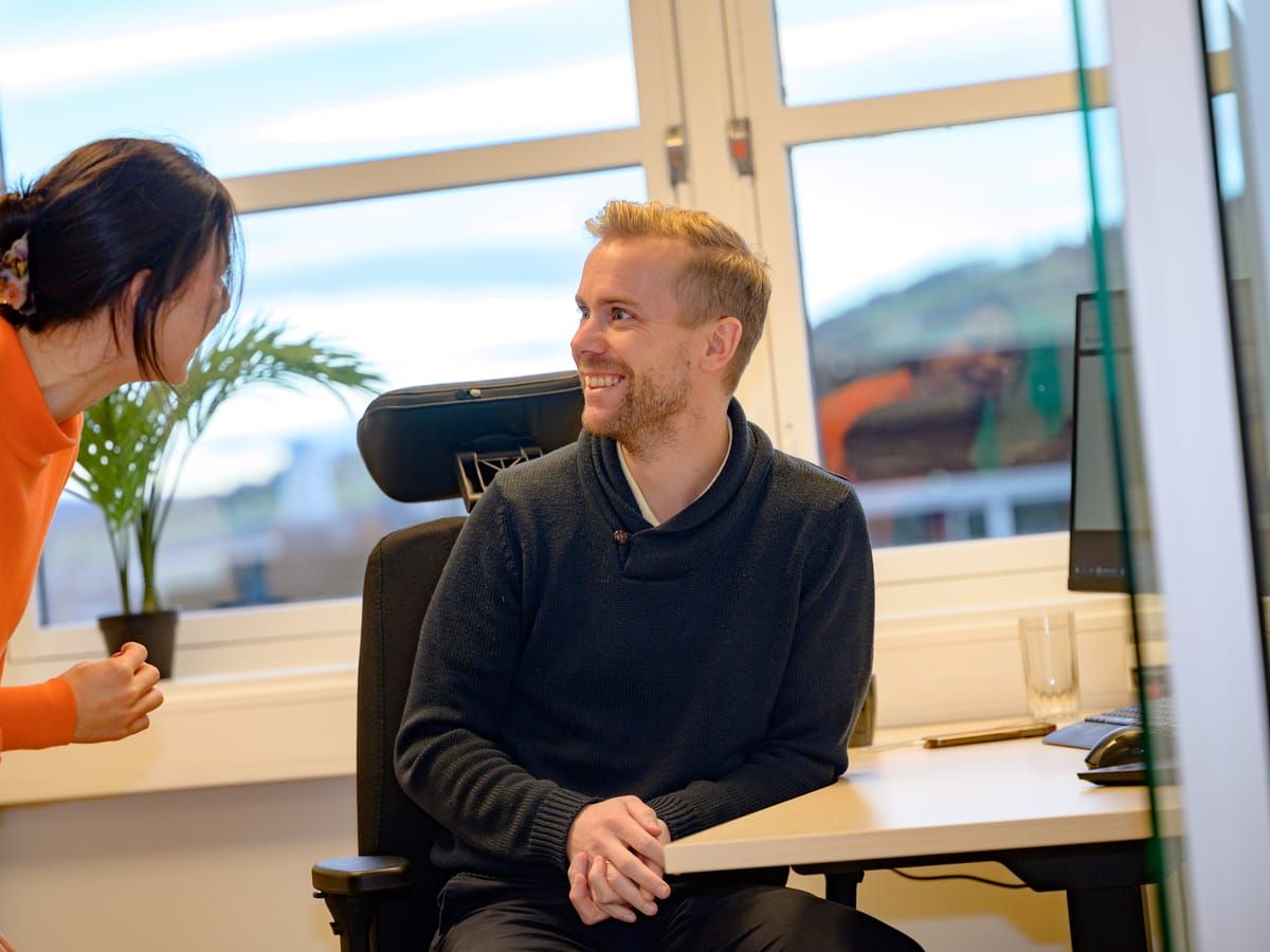 En kollega stikker innom for en prat ved skrivebordet